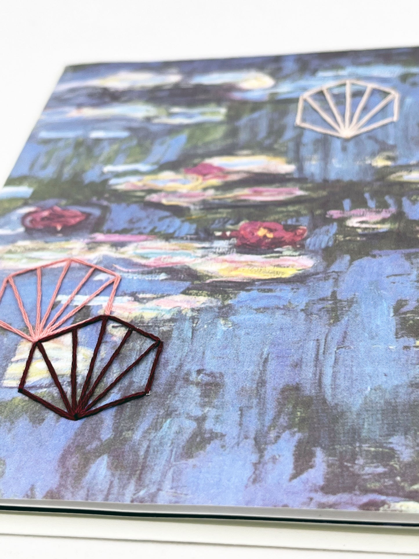 greeting card with print of Monet lily pads, hand embroidered with three art deco hexagons in peach and plums