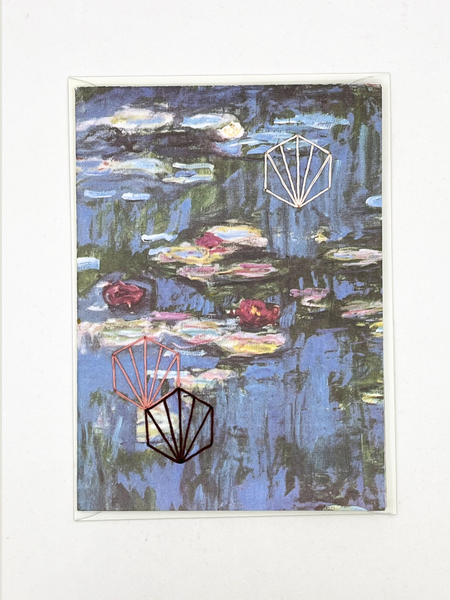 greeting card with print of Monet lily pads, hand embroidered with three art deco hexagons in peach and plums