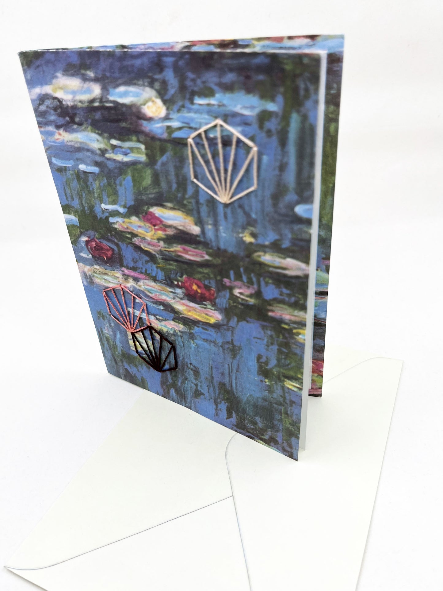 greeting card with print of Monet lily pads, hand embroidered with three art deco hexagons in peach and plums