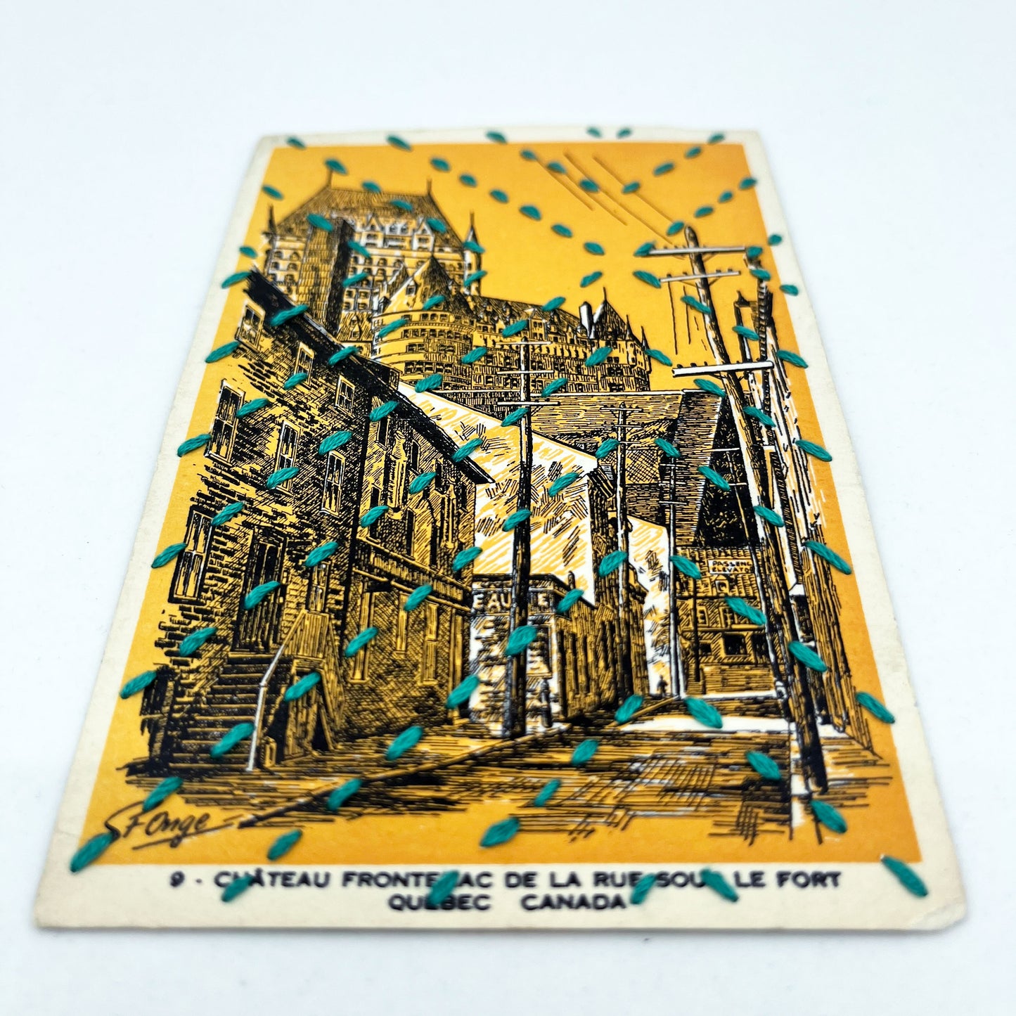 a golden yellow vintage postcard depicting a drawing of the Chateau Frontenac in Quebec, stitched over with running stitches in teal floss in a radiating X pattern