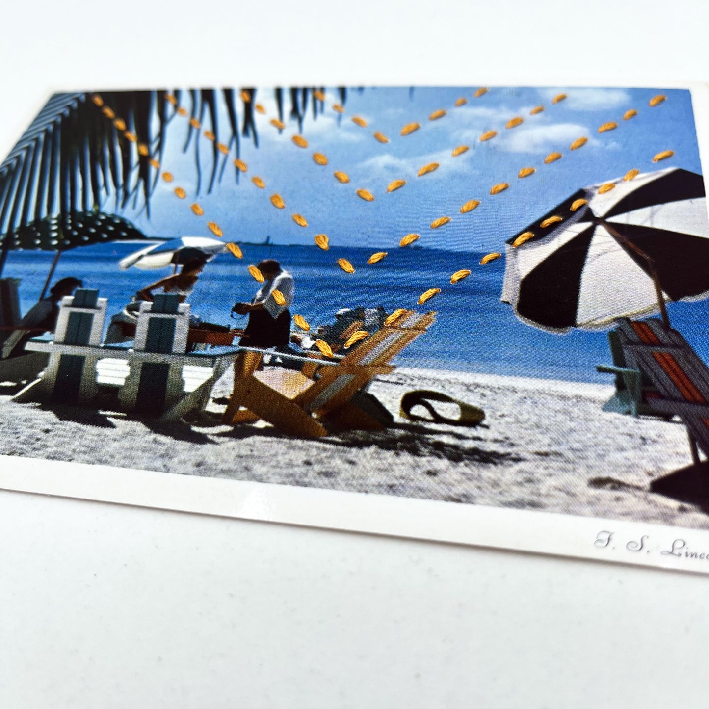 vintage postcard of a beach in the Bahamas with beach umbrellas and a palm tree, hand stitched with four rows of chevrons in yellow