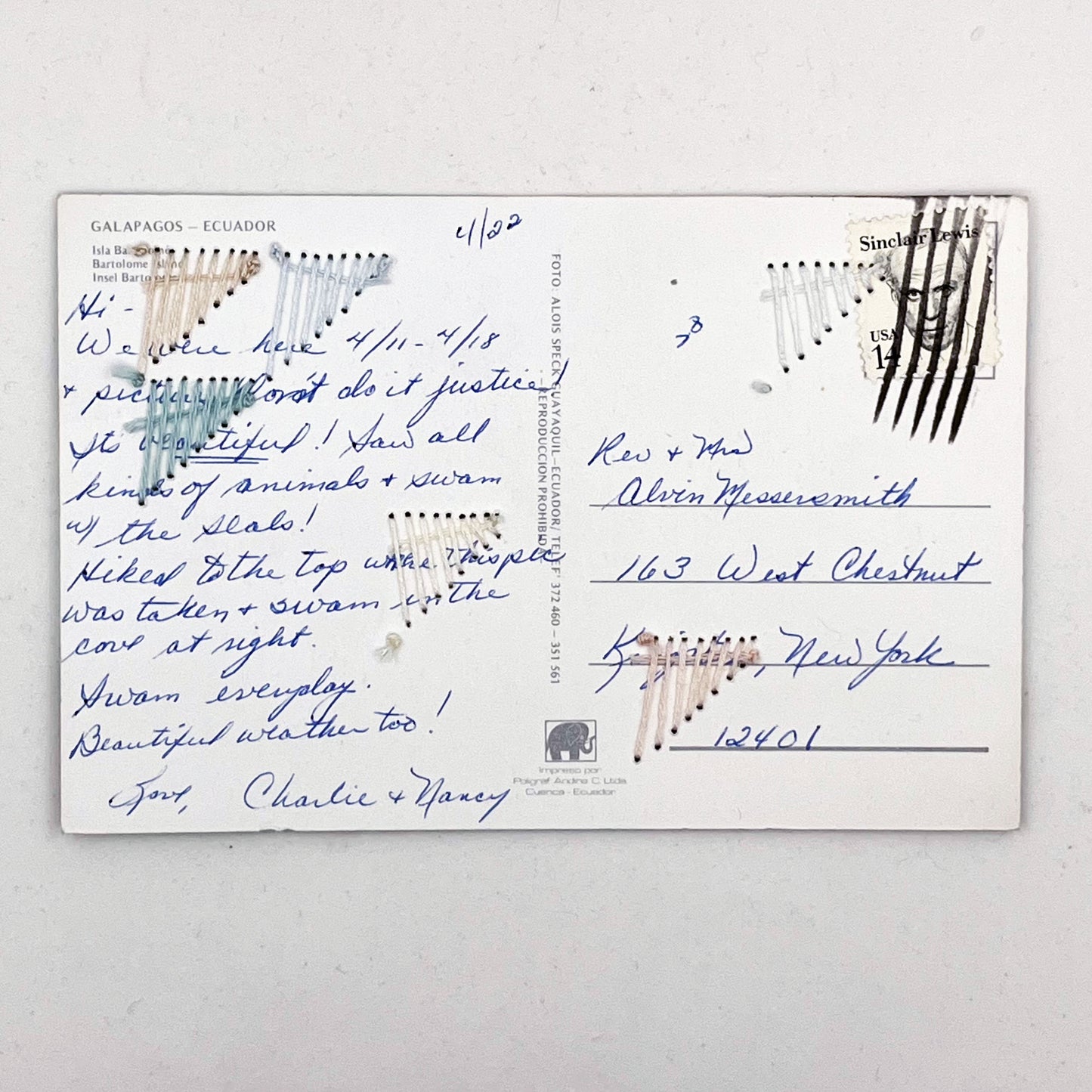 backside of a written on old postcard of part of Galapagos Ecuador, with hand embroidered triangles randomly placed in pastel greens blues peach and ivory