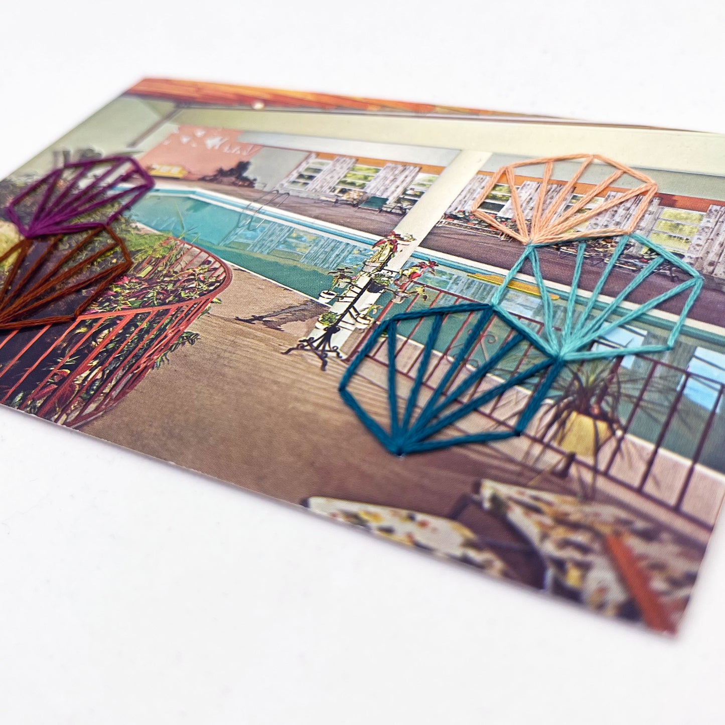 vintage postcard of an indoor pool, with art deco hexagons hand embroidered on it in aqua teal plum peach and brown