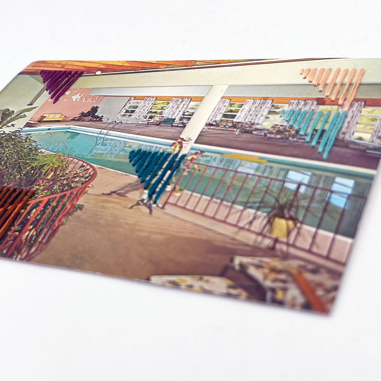 vintage postcard of an indoor pool, with randomly placed triangles hand embroidered on it in aqua teal plum peach and brown