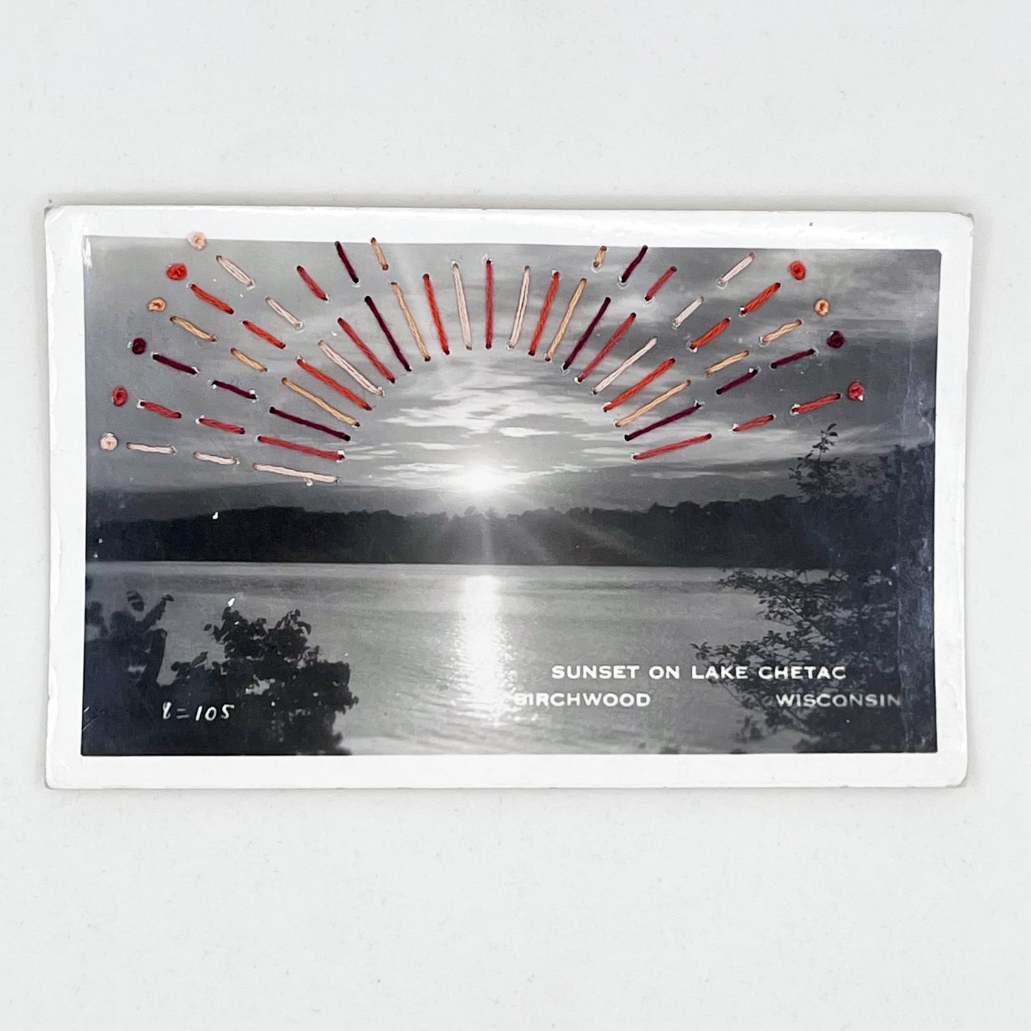an old postcard of Lake Chetac near Birchwood Wisconsin, with clay peach and plum hand embroidered rays coming off the setting sun