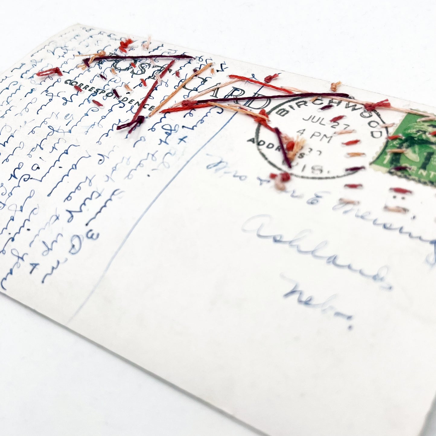close up angled view of the back of an old postcard of Lake Chetac near Birchwood Wisconsin, original handwritten note in cursive can be seen as well as postmark and stamp