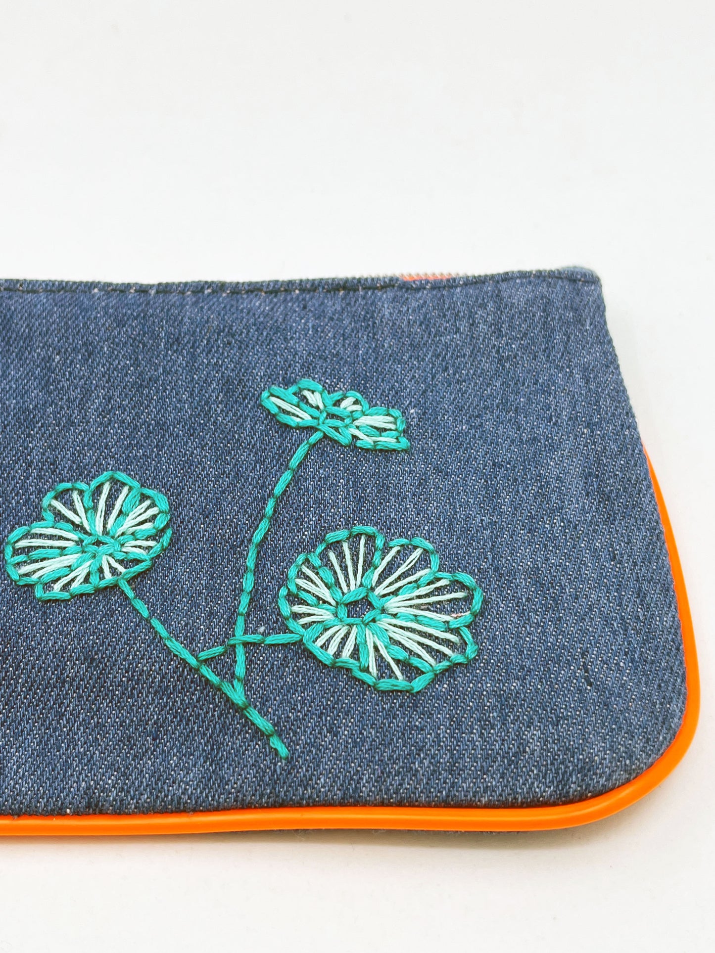 denim Ipsy zip pouch with neon orange piping and zipper, hand embroidered with aqua poppies