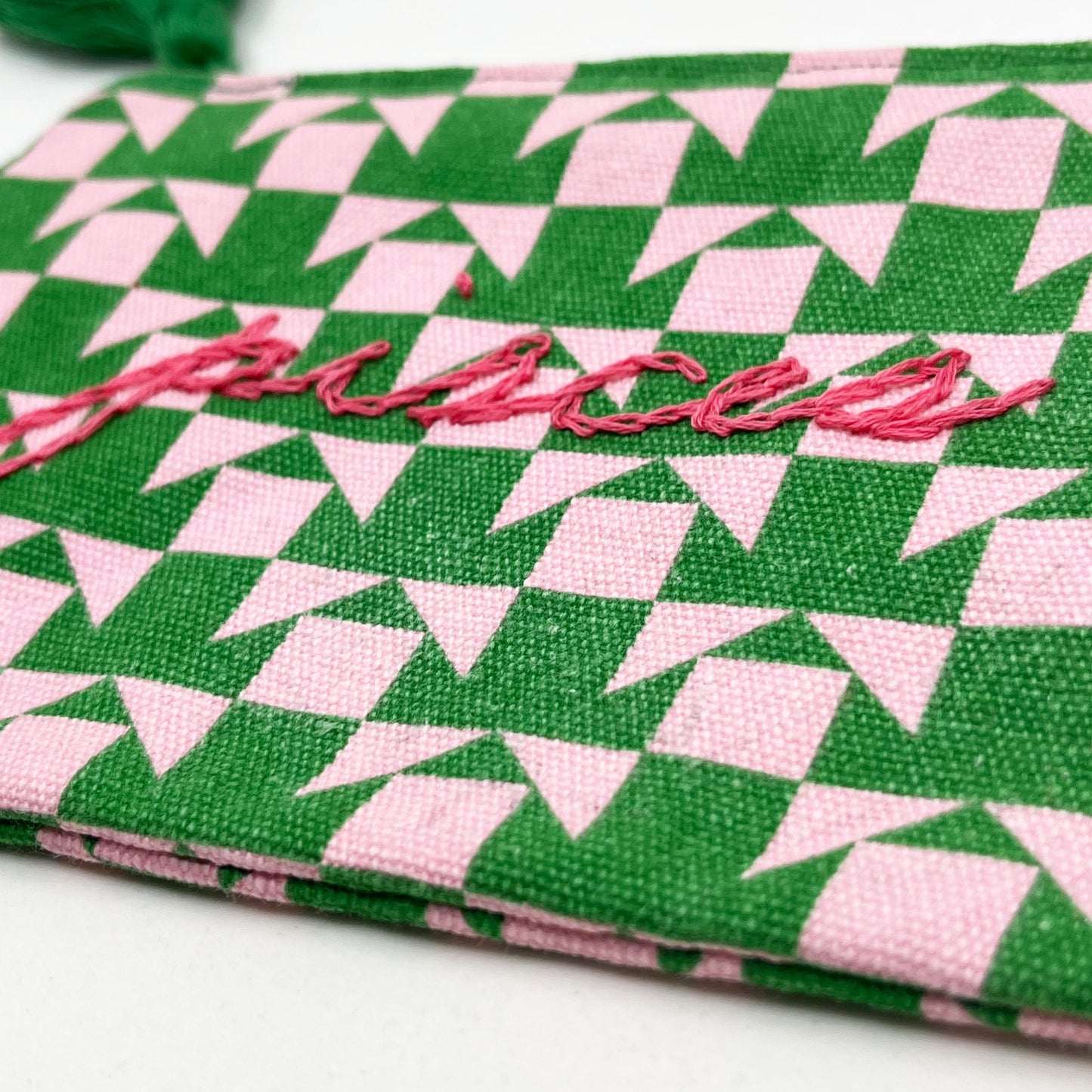 zip pouch with a pink and green geometric design on it hand embroidered in hot pink with the word pisces in chainstitch
