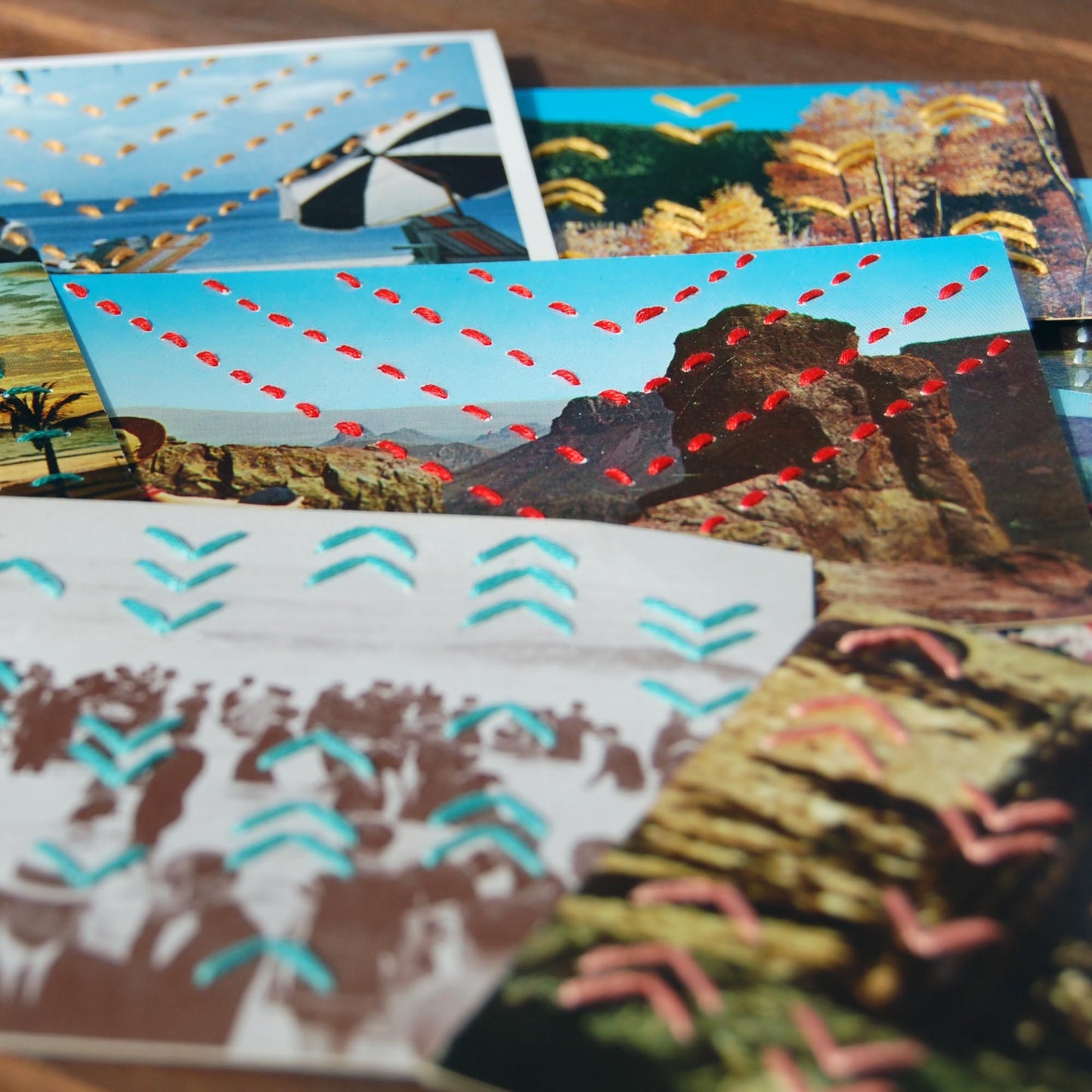 group of colorful vintage postcards hand stitched with different patterns of chevrons, in yellow, red, aqua and coral