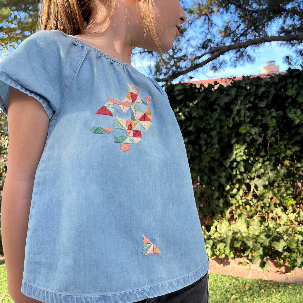 girl in chambray shirt with hand embroidered colorful triangles