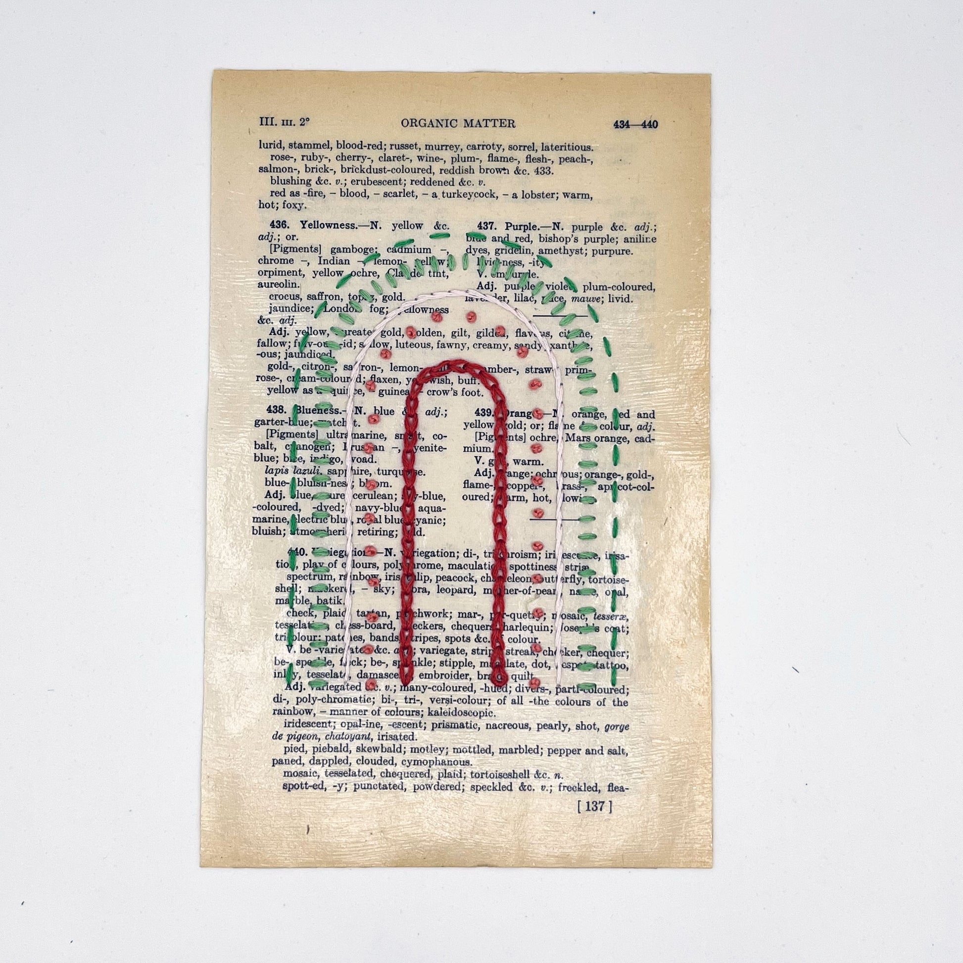 a vintage book page, embroidered with a rainbow of red, coral, peach and greens in different types of embroidery stitches, on a white background