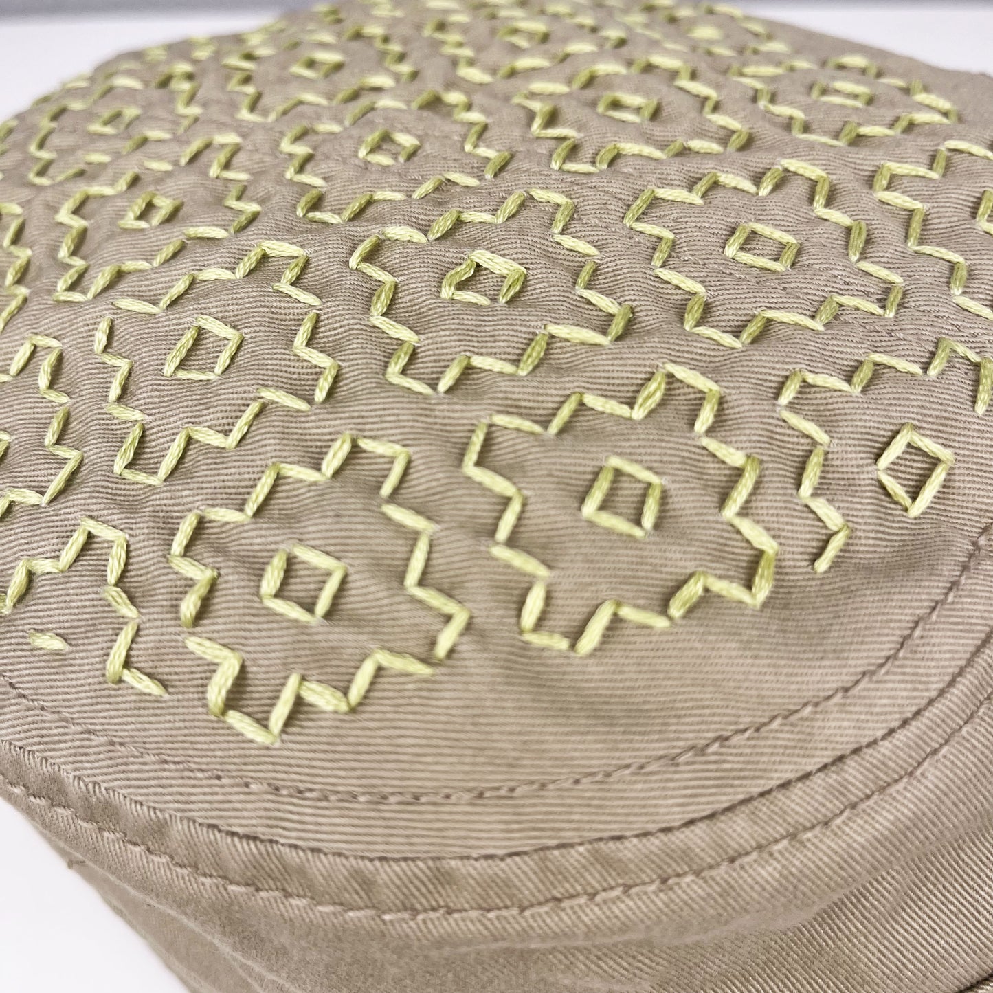 detailed new of persimmon sashiko pattern stitched in chartreuse thread on a tan cadet hat
