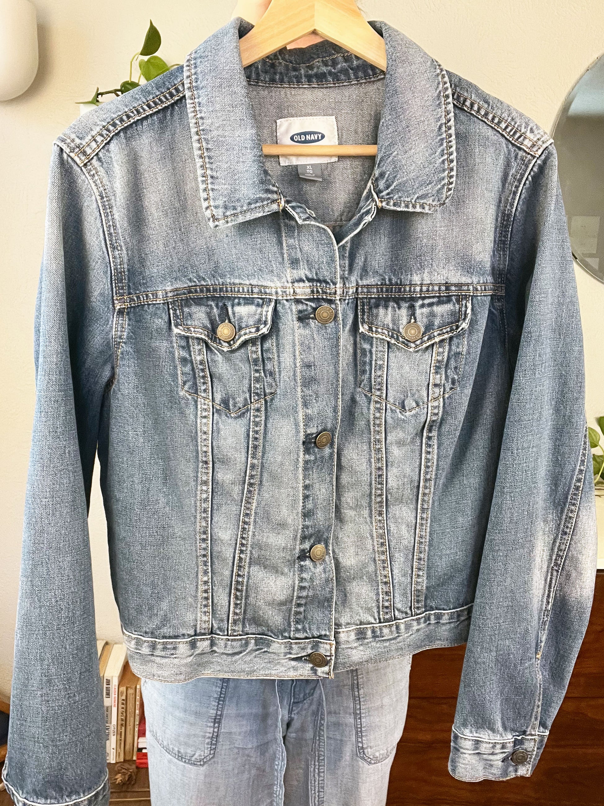 front view of a denim jacket being held up on a hanger