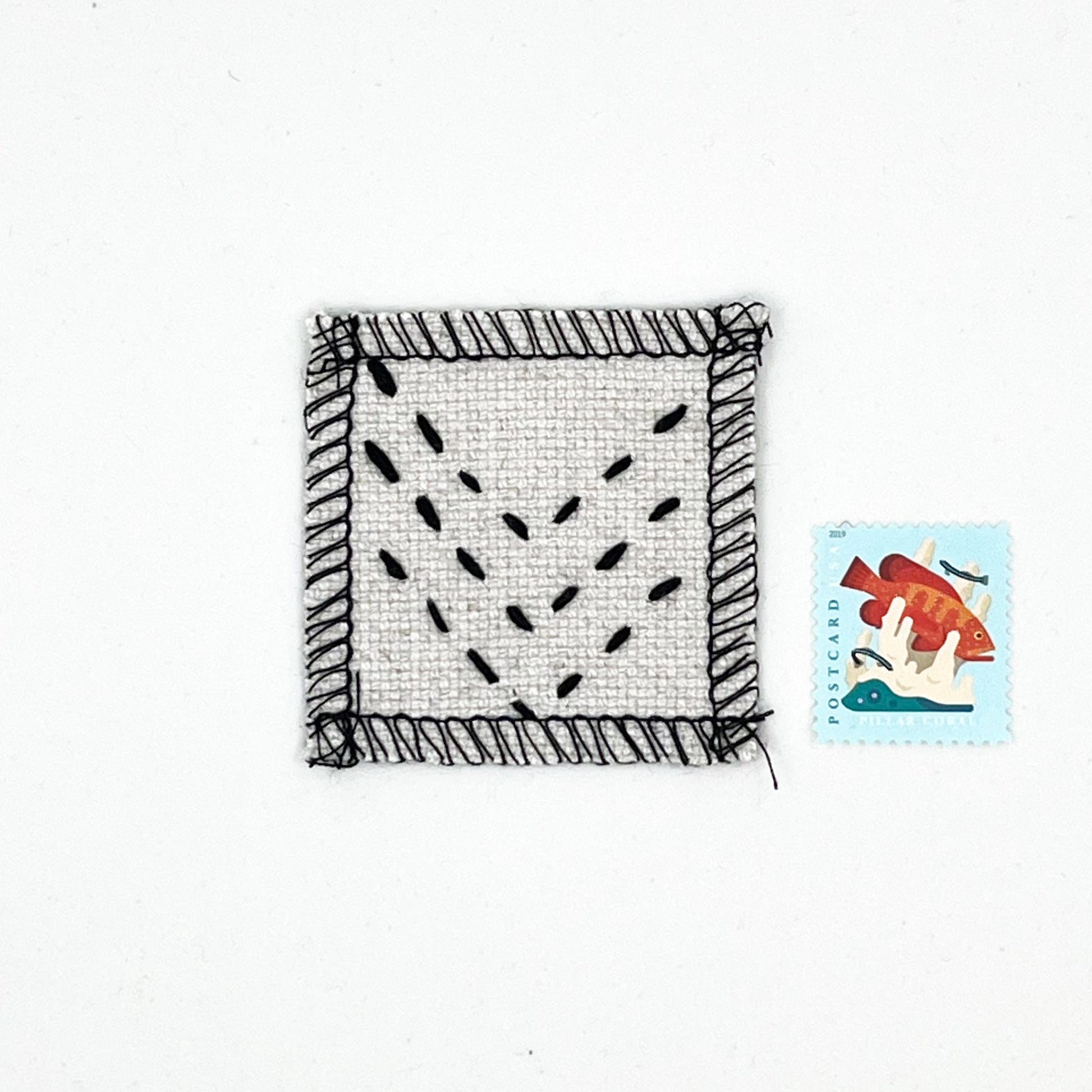 square natural colored patch with stitching in black of three chevron lines, next to a stamp for size comparison