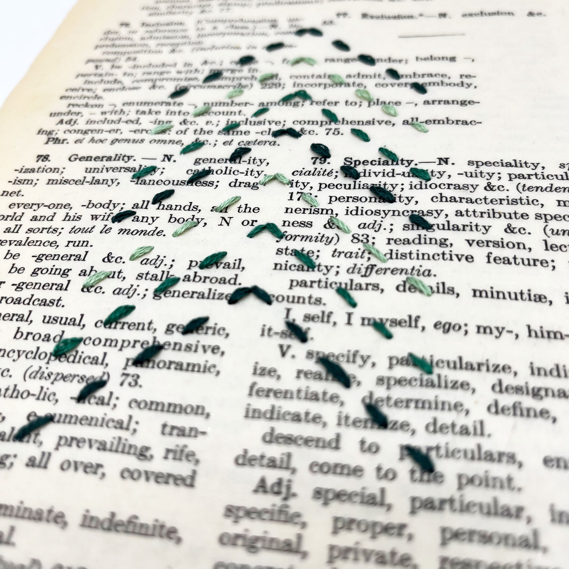 a vintage thesaurus page, embroidered with the shape of a Christmas tree made from running stitches forming a column of chevrons, in shades of pine green thread, on a white background. the page itself has words like speciality and generality on it