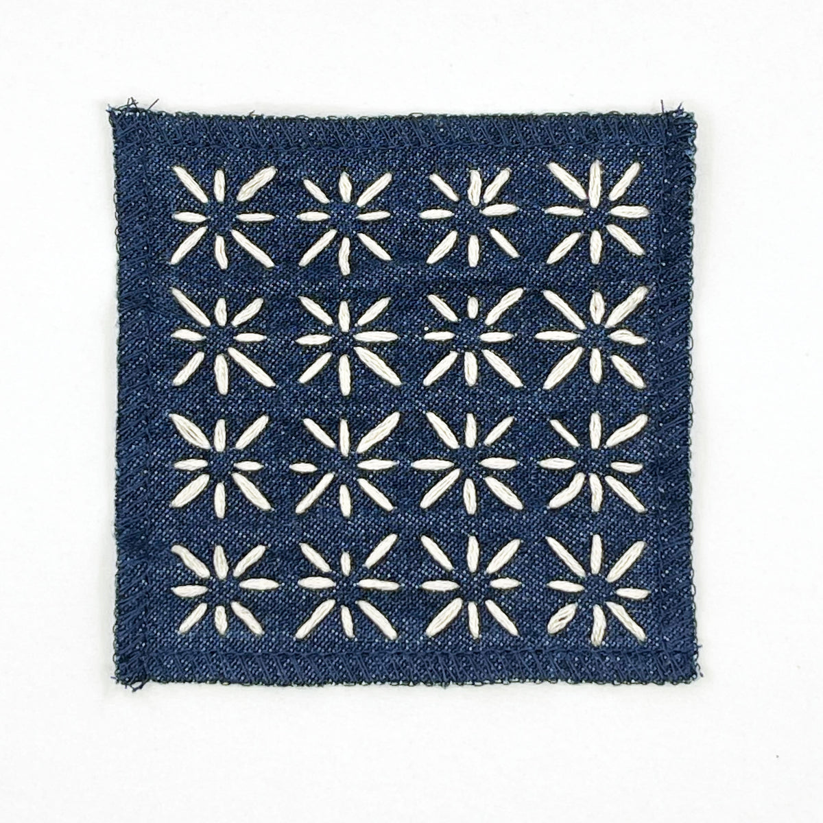 A square denim patch of with ivory star hand embroidery, displayed on a clean white background.