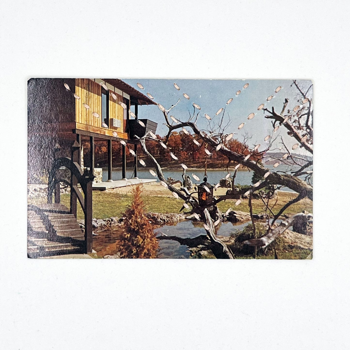 a vintage postcard of a Japanese inspired garden and house on a lake, hand stitched over with four rows of chevrons in running stitches with light pink thread, on a white background