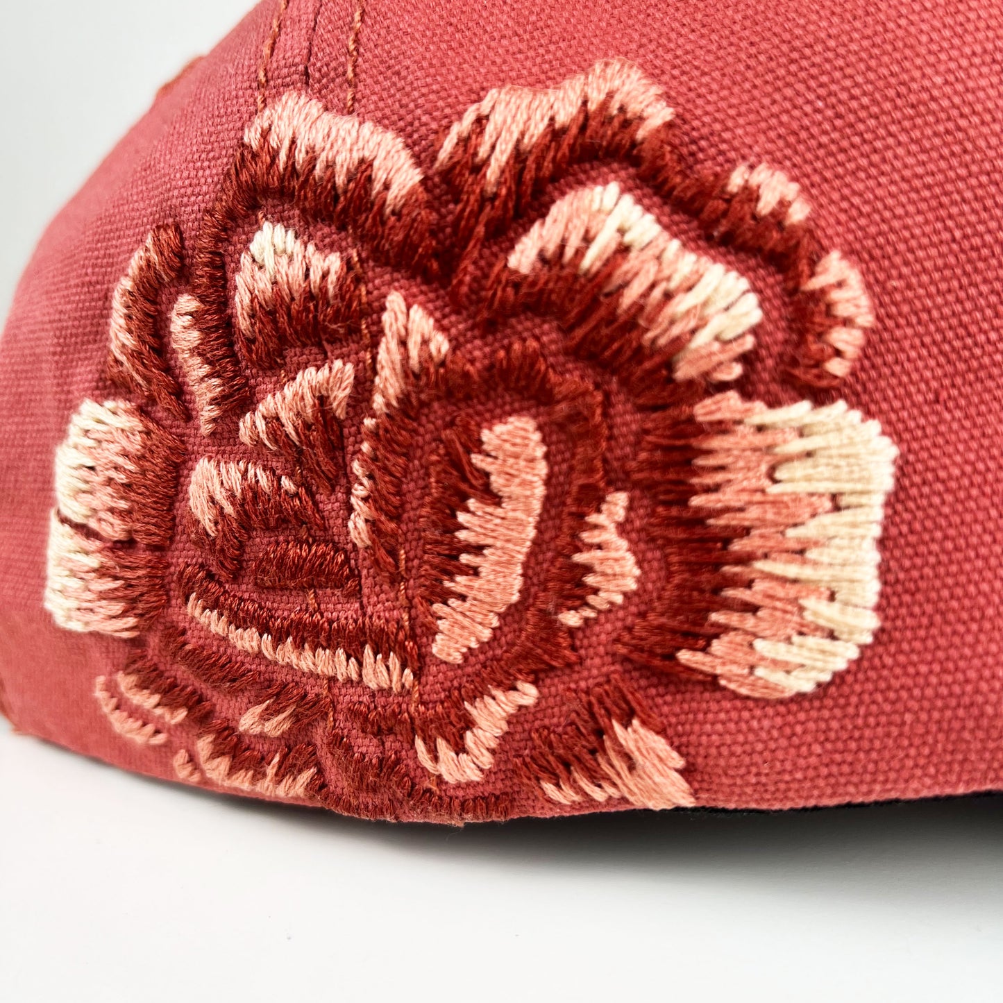 very close up view of hand embroidered peony in shades of terra cotta