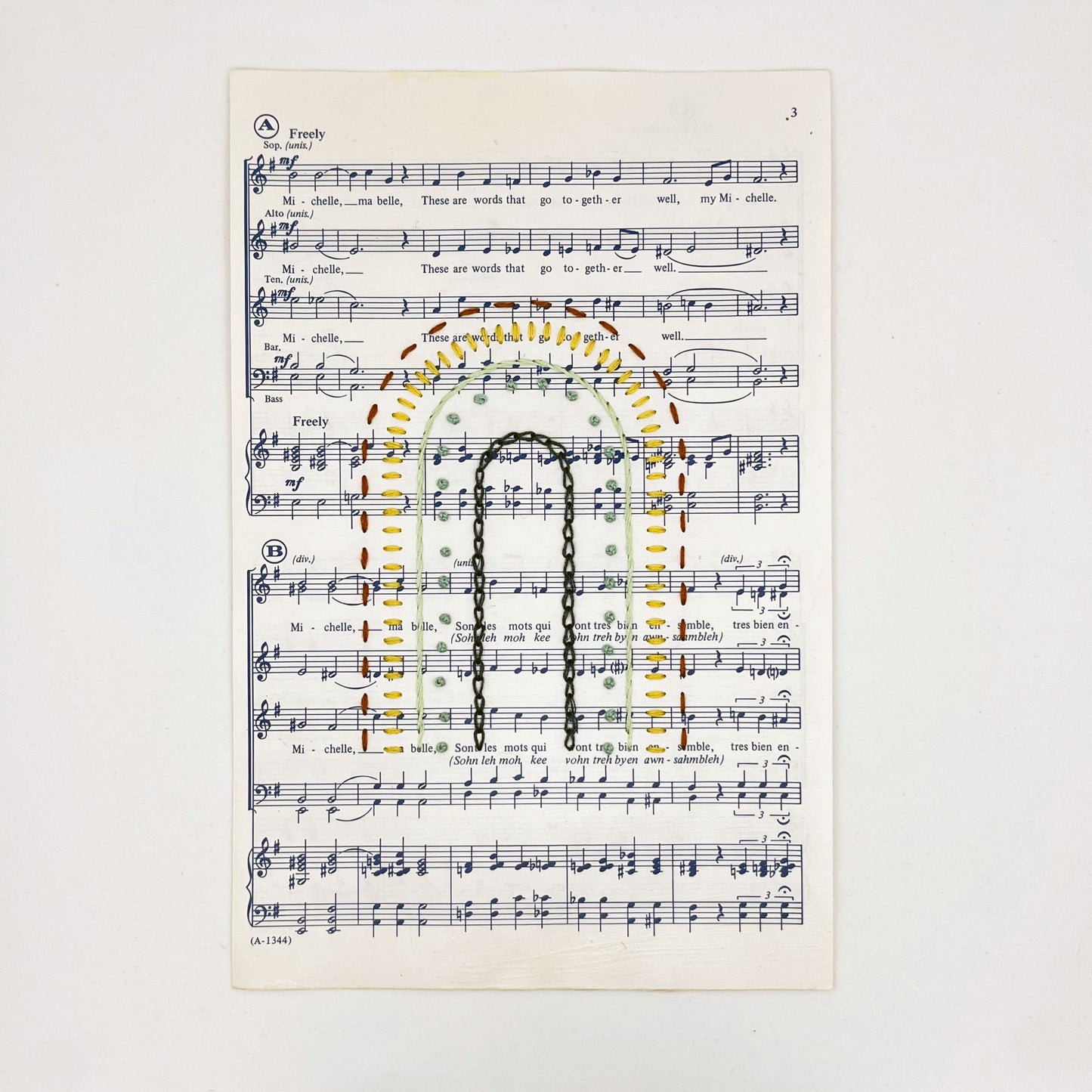 Sheet music for the song "Michelle", hand stitched on in the shape of a rainbow with different types of stitches like chainstitch in dark blue, french knots in green, whipped backstitch in light green, running stitch in red, on a white background