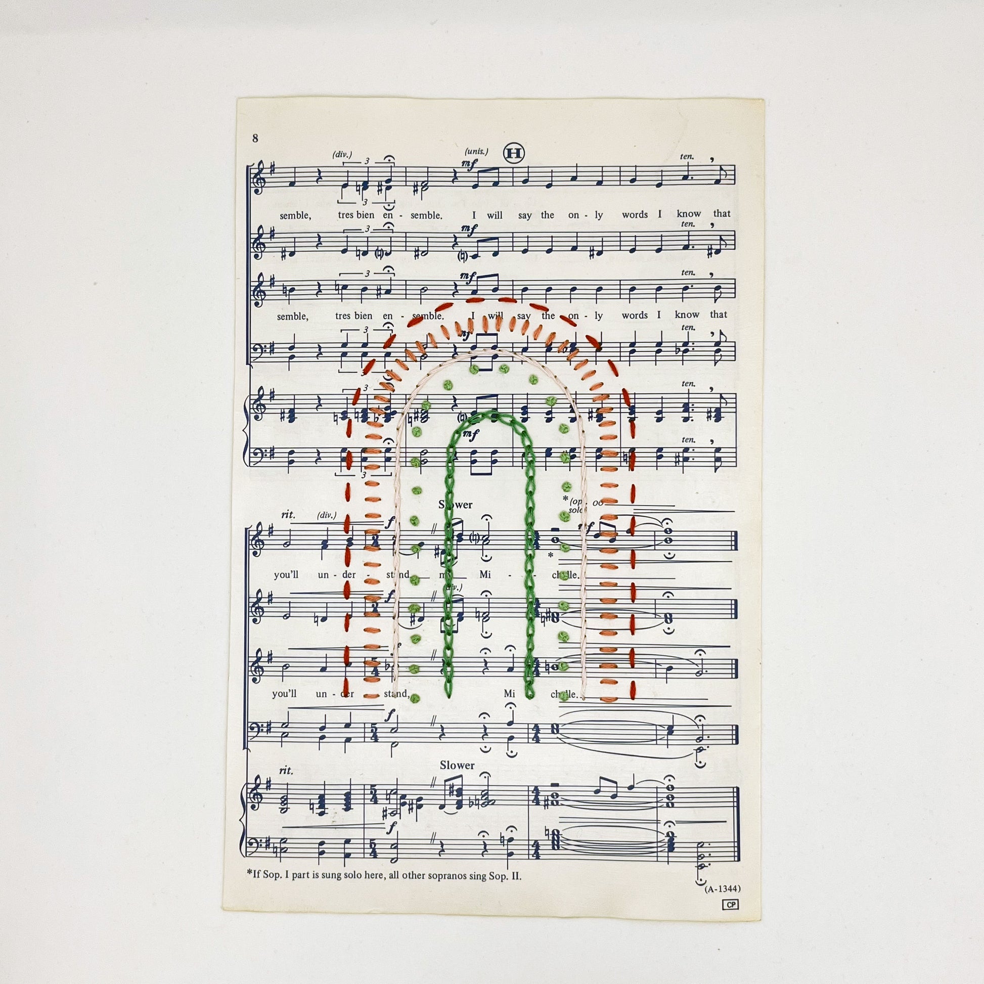 Sheet music for the song "Michelle", hand stitched on in the shape of a rainbow with different types of stitches like chainstitch in dark green, french knots in light green, whipped backstitch in pink, running stitch in red, on a white background