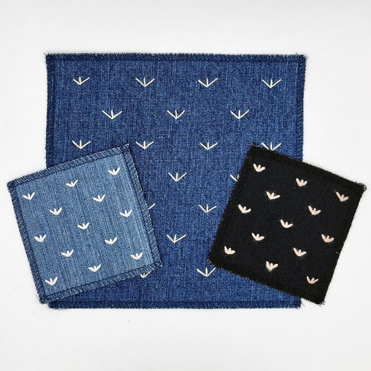 a group of sew in patches made from denim and black canvas fabric, with stitches that look like birds feet or sprouts spread out in a diamond pattern, on a white background