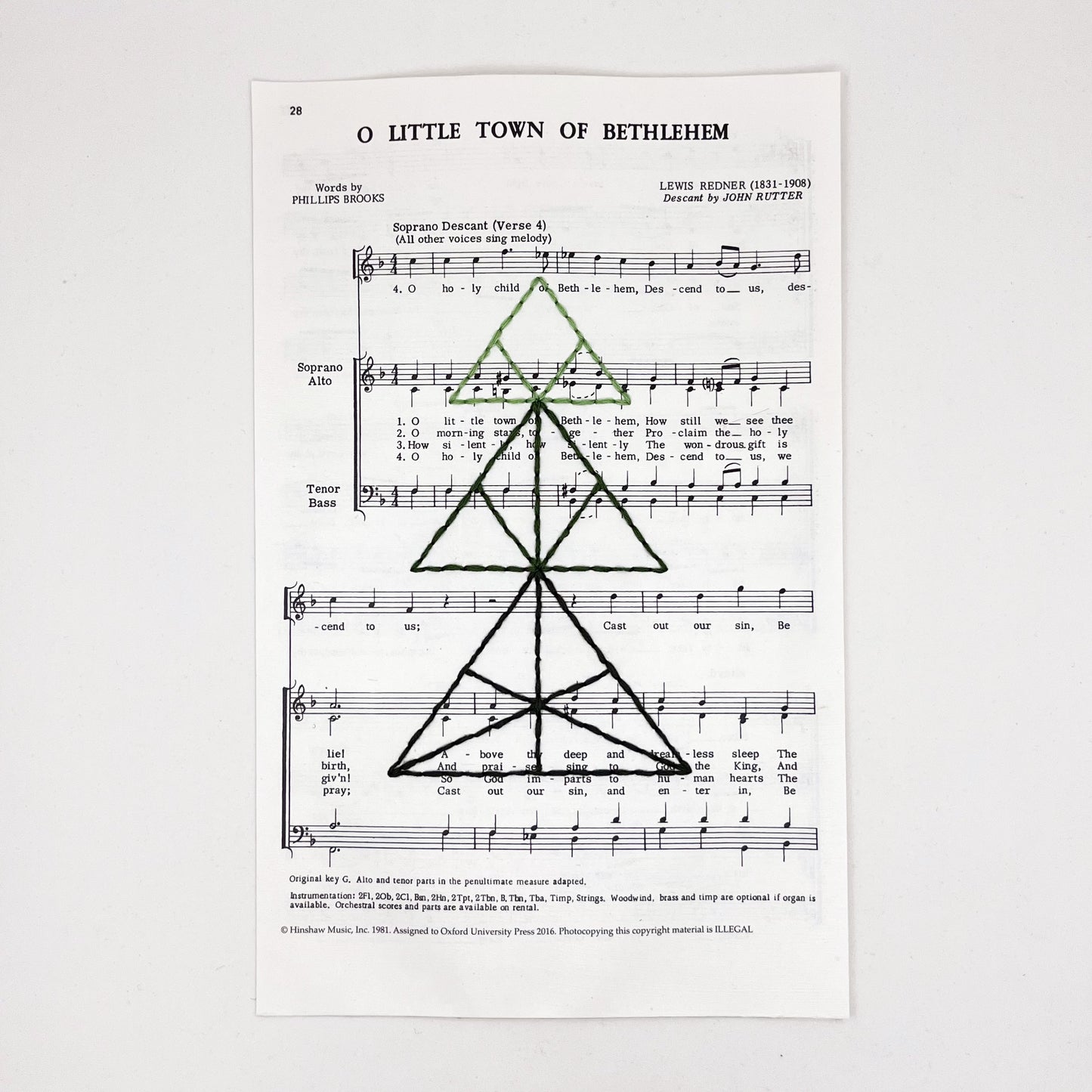 sheet music from the Christmas "O Little Town of Bethlehem", hand stitched over with a Christmas tree made from triangles, in shades of green thread