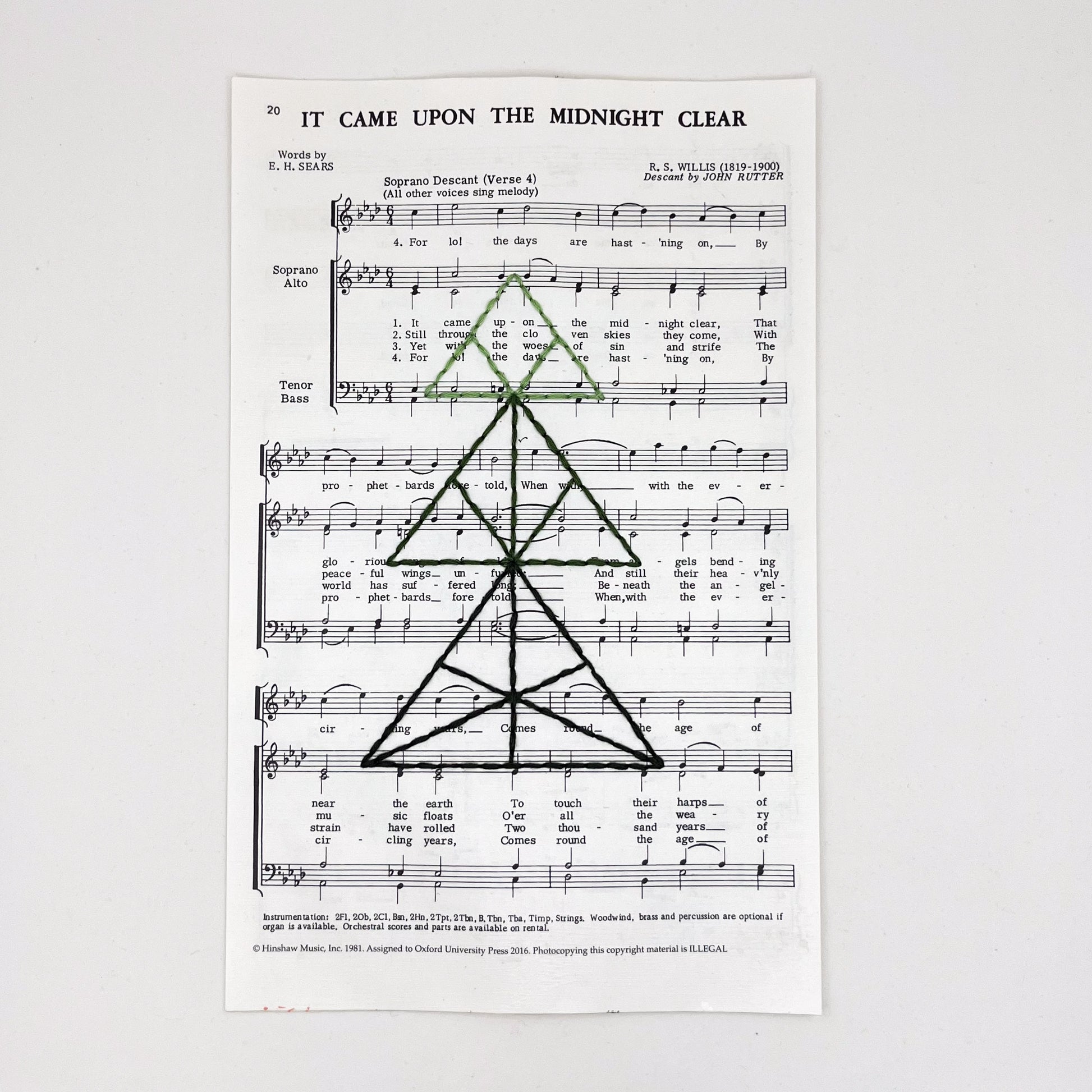 sheet music from the Christmas song "It Came Upon the Midnight Clear", hand stitched over with a Christmas tree made from triangles, in shades of green thread