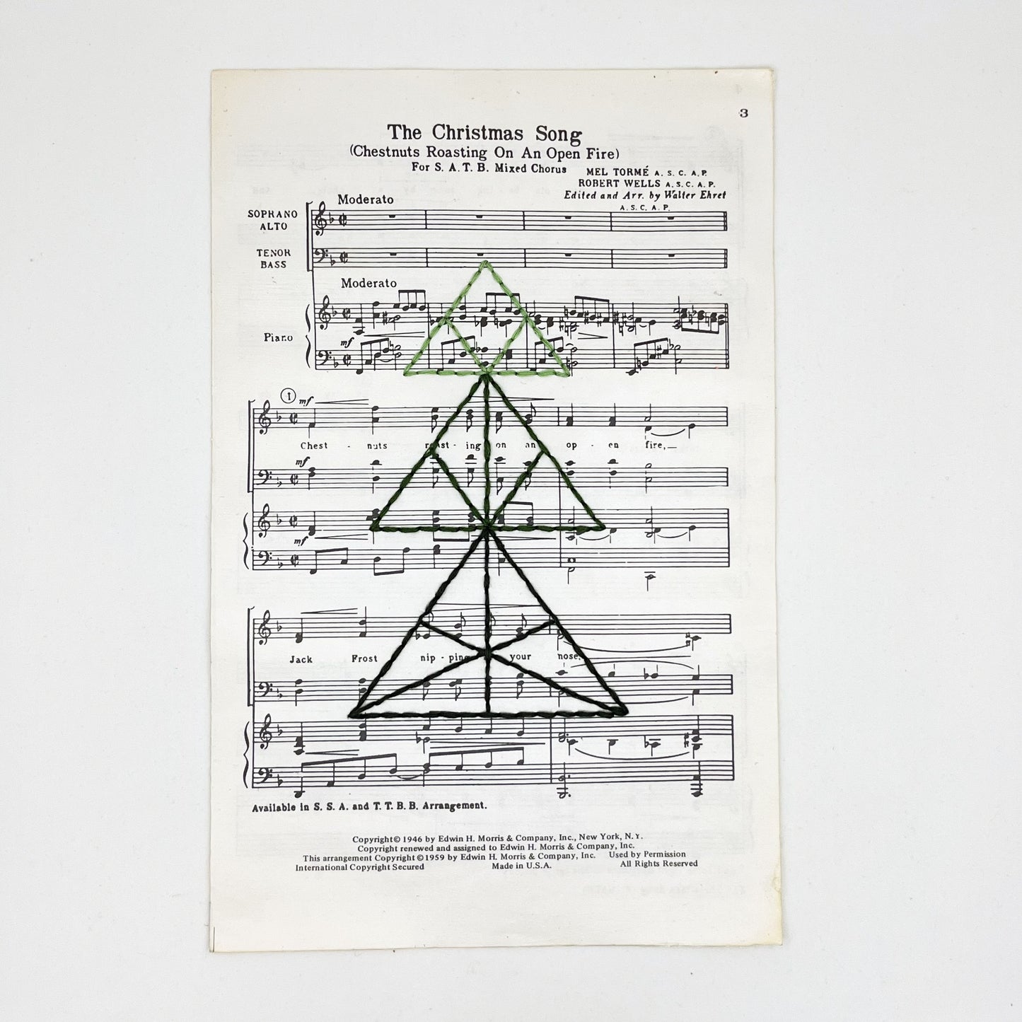 sheet music from "The Christmas Song", hand stitched over with a Christmas tree made from triangles, in shades of green thread